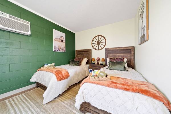 Two twin beds with white quilts, orange throws and welcome baskets of toiletries
