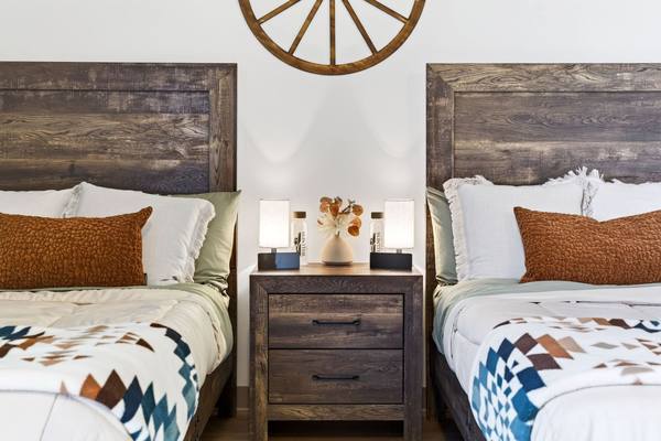 Two twin beds with reclaimed wood headboards flanking a shared nightstand with lamps and flowers