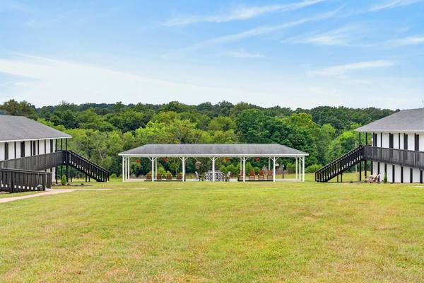 Wide green lawn between two residence buildings looking toward the pavilion and the tree line