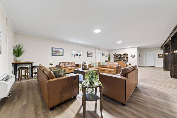 Four leather sofas around a wooden coffee table in a bright lounge with plaid pillows and potted plants