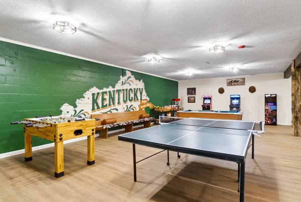 Game room with foosball and ping pong tables, arcade cabinets and a painted Kentucky mural
