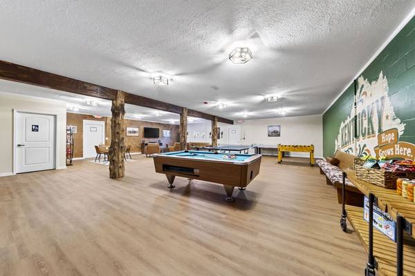 Recreation room with a pool table, ping pong table, foosball and a Kentucky mural on a green wall