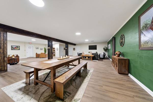 Long farmhouse dining table with benches in an open community room with lounge seating beyond