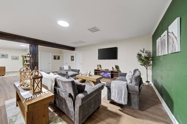 Grey upholstered armchairs with throws around a coffee table, lit fireplace and exposed wood beam overhead