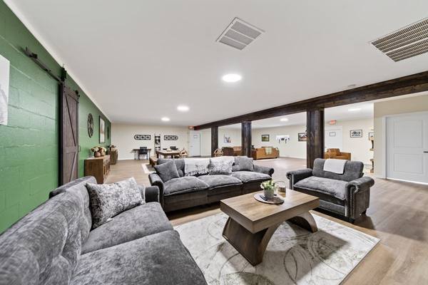Grey sofas and a wood coffee table in a long common room with a sliding barn door and green wall