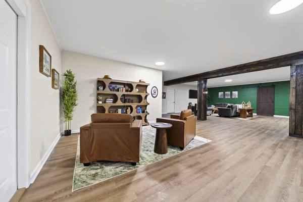 Two leather armchairs on a green rug beside a wooden bookshelf, with the green lounge visible beyond the beams