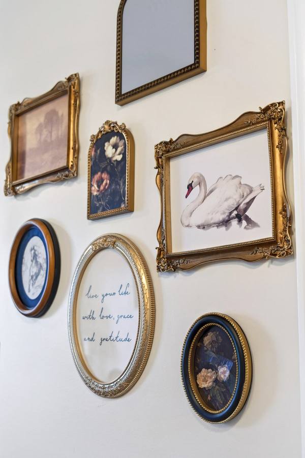 Cluster of gilt-framed prints and a swan painting around a quote about love, grace and gratitude