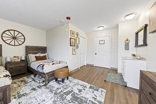 Bedroom with a twin bed, framed gallery wall and a white in-room vanity sink with mirror