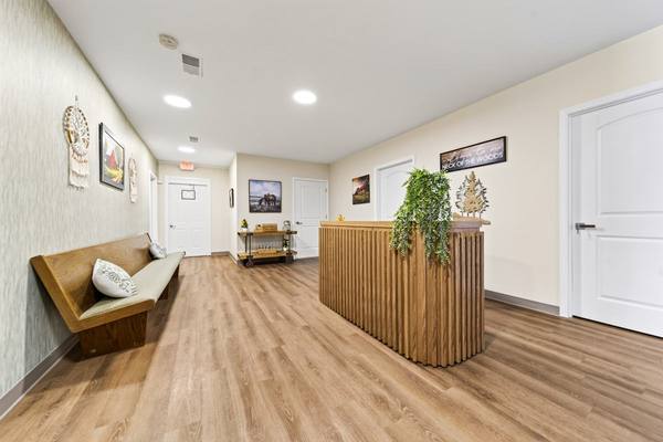 Wooden bench with cushions and pillows across from a slatted front desk trailing a leafy plant
