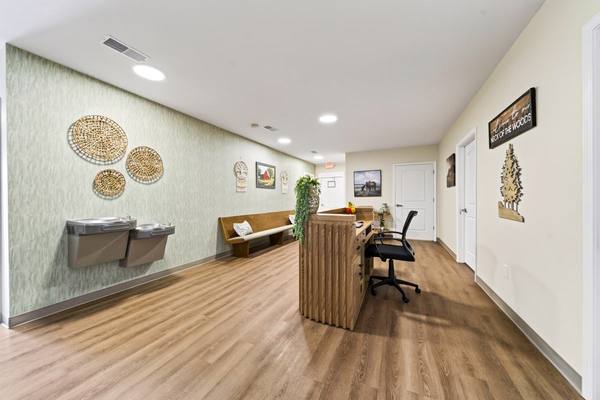 Check-in desk and chair beside drinking fountains and a bench under woven wall baskets