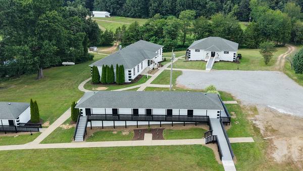 Aerial looking down over the residence buildings toward the gravel drive and the main house