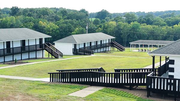 Residence building with black railed decks, the open pavilion and a second building beyond