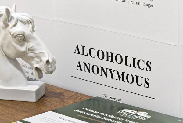 White horse bust beside a wall panel printed with the title page of Alcoholics Anonymous