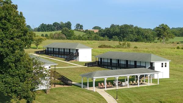 Aerial of the residence buildings and pavilion surrounded by open mown farmland and woods