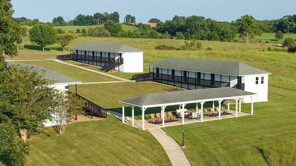 Aerial of the residence wings with the pavilion and lawn between them and woods along the edge