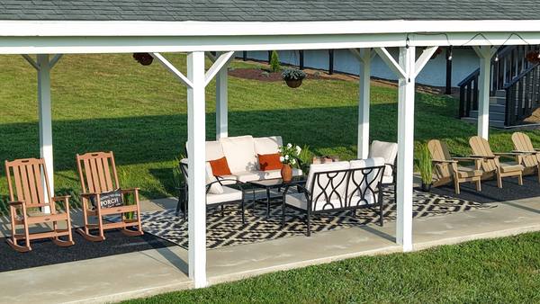 Rocking chairs and cushioned outdoor sofas under the pavilion with hanging flower baskets