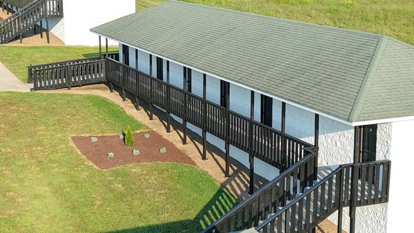 Residence building with a black railed deck running its length and stairs down to a planted bed