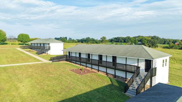 Residence wing with deck and stairs looking out over open fields to the tree line