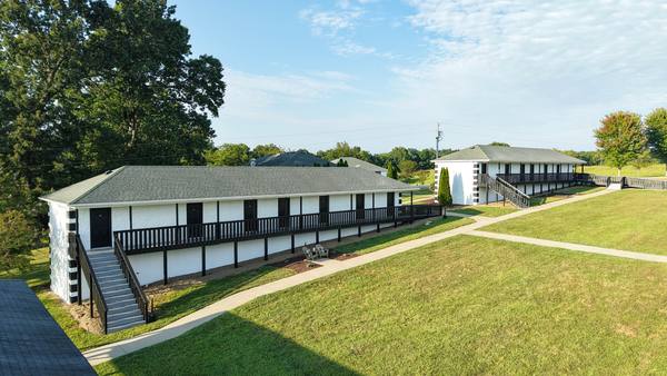 Two residence wings across mown grass with open countryside stretching out behind them