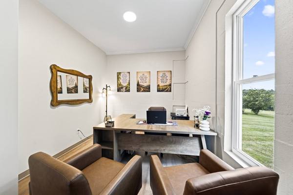 Small office with two brown leather armchairs pulled up to a desk beside a sunlit window