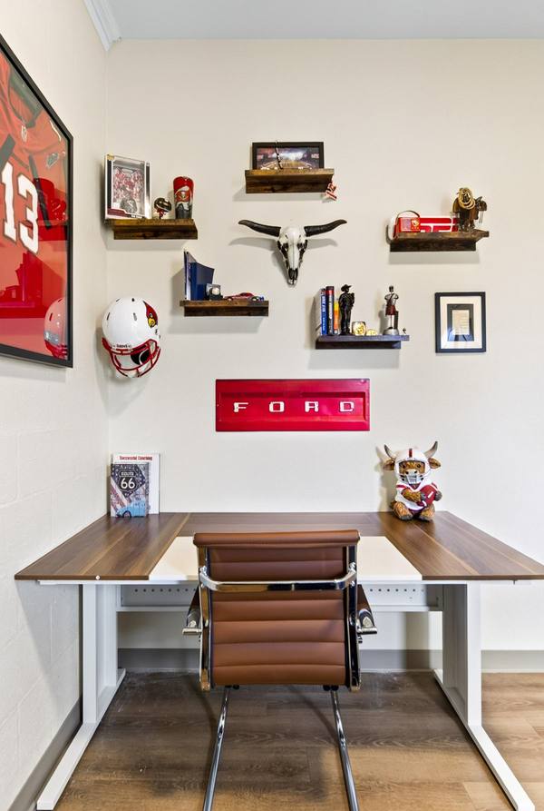 Desk below floating shelves holding a football helmet, longhorn skull and a red Ford tailgate sign