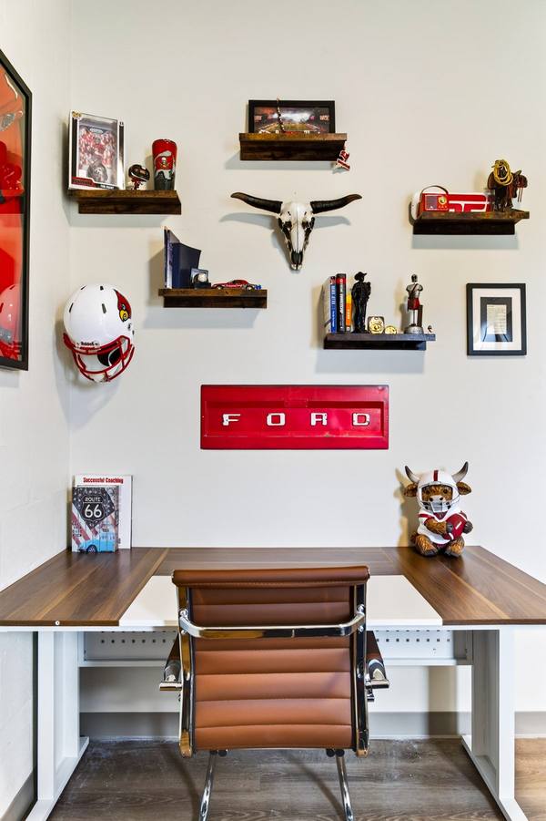 Office desk under shelves of Louisville Cardinals memorabilia, a football helmet and a red Ford tailgate