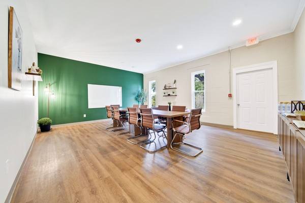 Large meeting room with a conference table, leather chairs and a whiteboard on a green accent wall