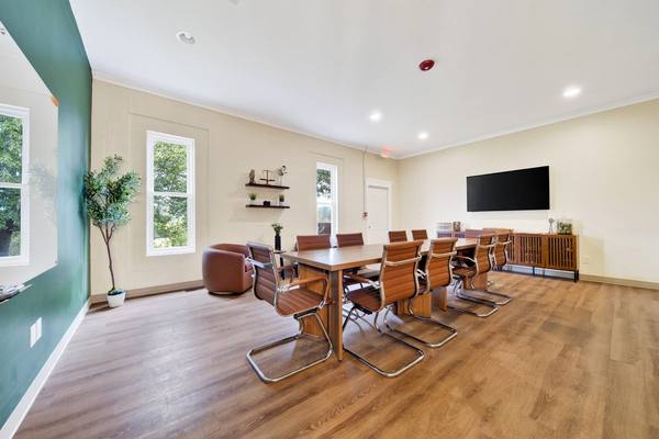 Conference room with a long wood table, tan leather chairs and a wall-mounted screen