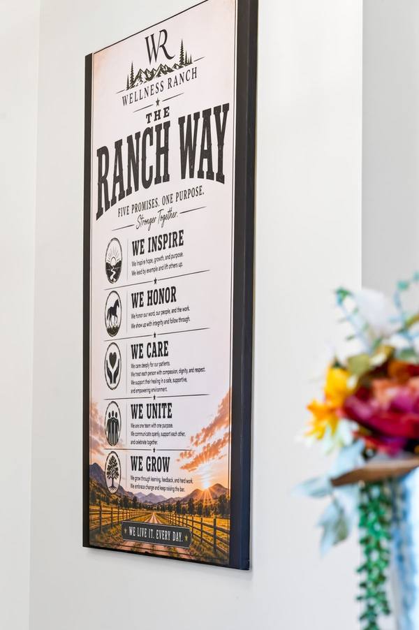 Framed Ranch Way sign on a white wall listing five promises: inspire, honor, care, unite, grow