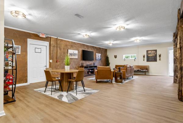 Open common room with a round dining table, board game shelf, TV seating area and copper accent wall