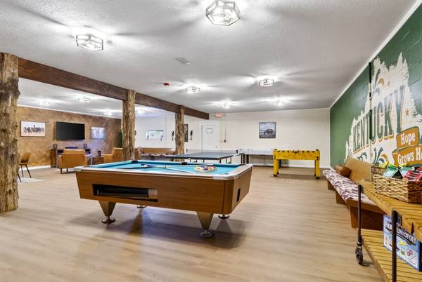 Game room with a pool table, ping pong and foosball beside a painted Kentucky mural