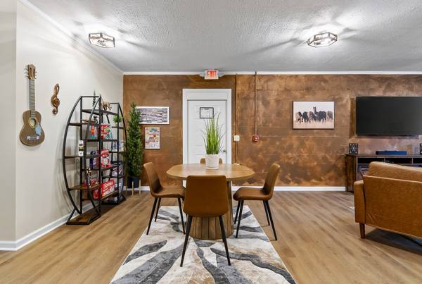 Round table with four chairs beside a shelf stacked with board games and a guitar hung on the wall