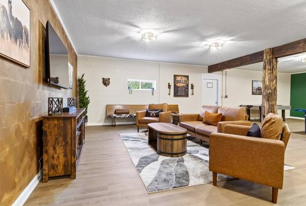 Lounge with leather couches facing a wall-mounted TV, barrel coffee table and exposed timber post