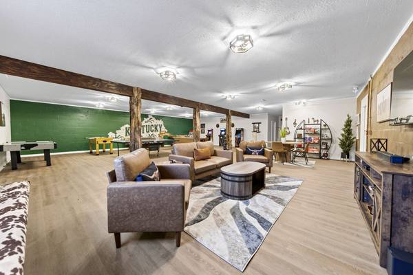 Open rec room with air hockey, foosball, ping pong and arcade games behind leather sofas