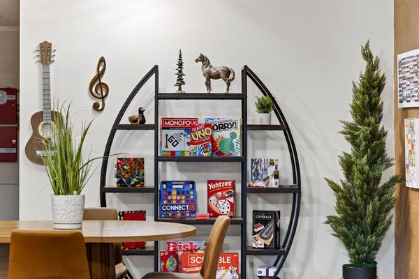 Arched shelf stocked with Monopoly, Uno, Yahtzee and other board games beside a wall-hung guitar