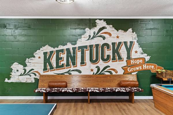 Painted Kentucky state mural reading Hope Grows Here above a long cowhide bench