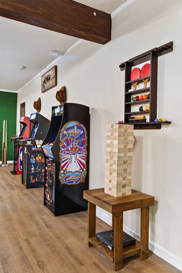 Row of arcade cabinets, a giant Jenga tower and a wall rack of ping pong paddles and pool balls