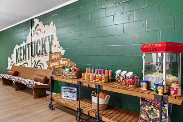 Snack cart with drinks, candy jars, a popcorn machine and board games beside cowhide benches