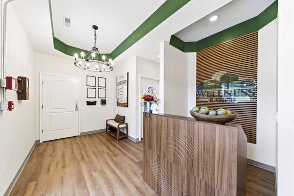 Front reception desk under a ring chandelier, with the Wellness Ranch logo on a wood slat wall