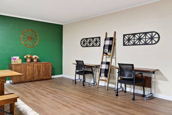 Small room with two desks and rolling chairs, a blanket ladder and a wagon wheel on a green wall