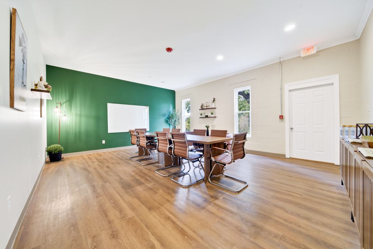 Large meeting room with a conference table, leather chairs and a whiteboard on a green accent wall